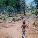 Boy heading to informal creek that operates as a laundry in Sierra Leone.